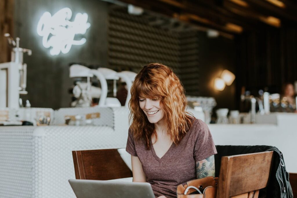 woman with red hair at a cafe with her laptop