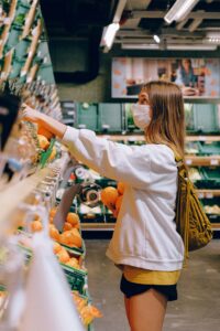 Girl in white long sleeve shirt grabbing produce at a store